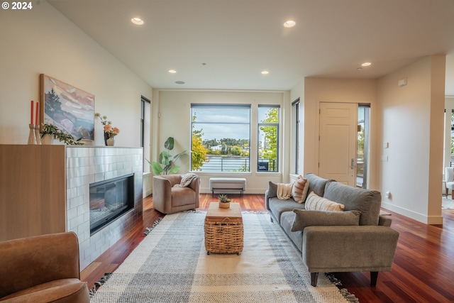 living area featuring baseboards, recessed lighting, a tile fireplace, and wood finished floors