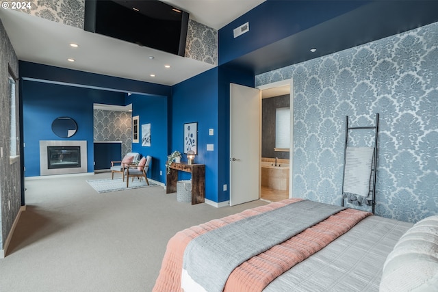 bedroom featuring a glass covered fireplace, baseboards, recessed lighting, carpet flooring, and visible vents