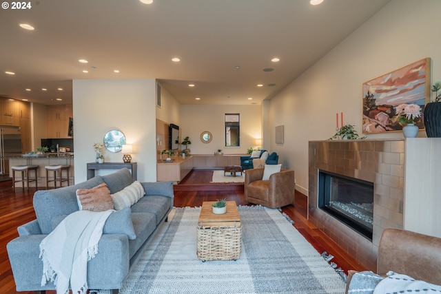 living room with a tile fireplace and dark hardwood / wood-style flooring