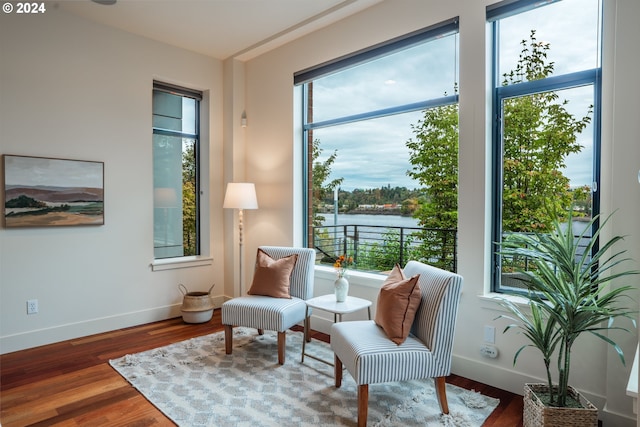 sitting room featuring a water view, plenty of natural light, and dark hardwood / wood-style floors