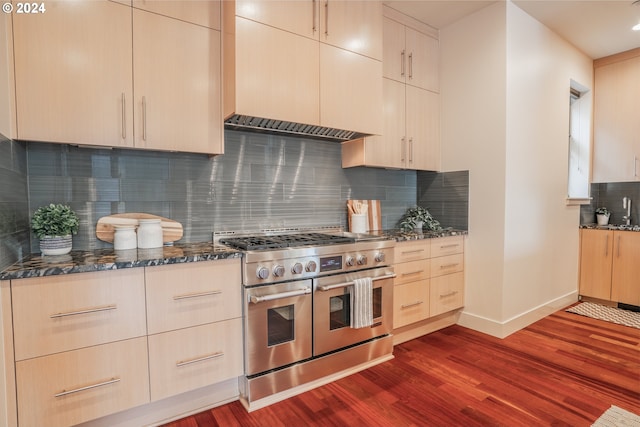 kitchen with dark stone countertops, tasteful backsplash, baseboards, dark wood-style floors, and double oven range