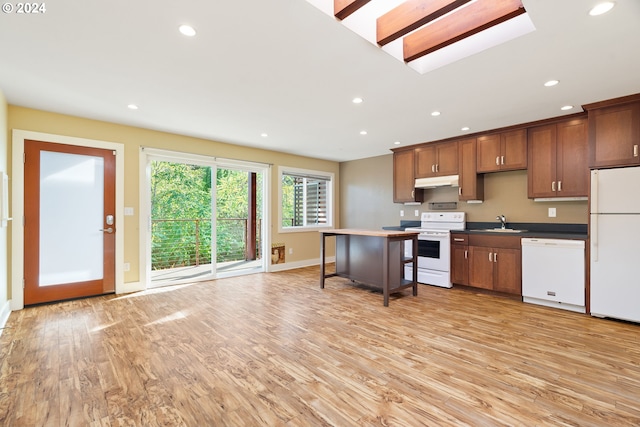 kitchen with a kitchen breakfast bar, light wood-type flooring, sink, and white appliances