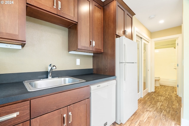 kitchen with light wood-type flooring, white appliances, and sink