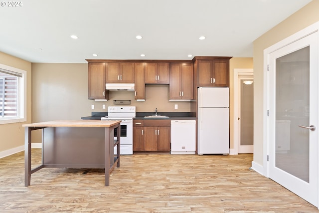 kitchen with a breakfast bar area, light hardwood / wood-style floors, sink, and white appliances