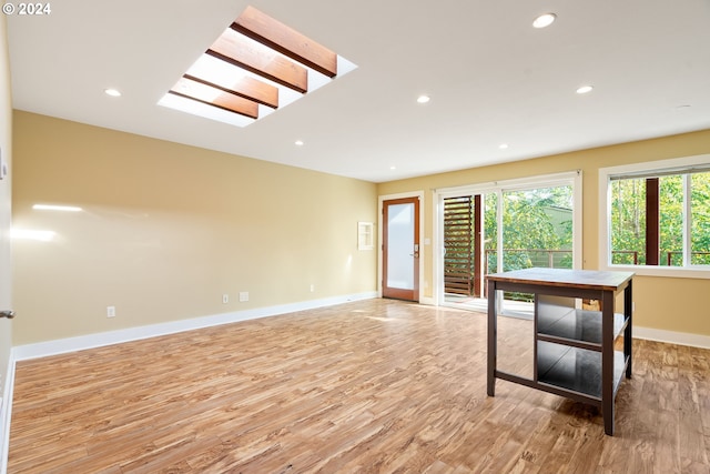 unfurnished room with light wood-type flooring and a skylight