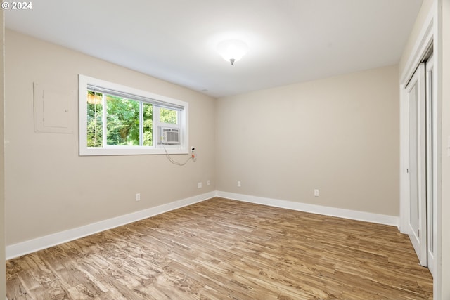 unfurnished bedroom featuring cooling unit, hardwood / wood-style floors, and a closet