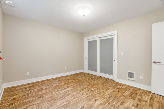 unfurnished bedroom with light hardwood / wood-style flooring, heating unit, and a closet