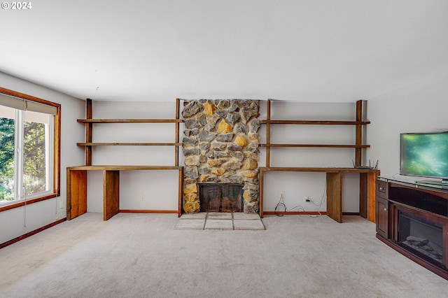 unfurnished living room featuring a stone fireplace and carpet