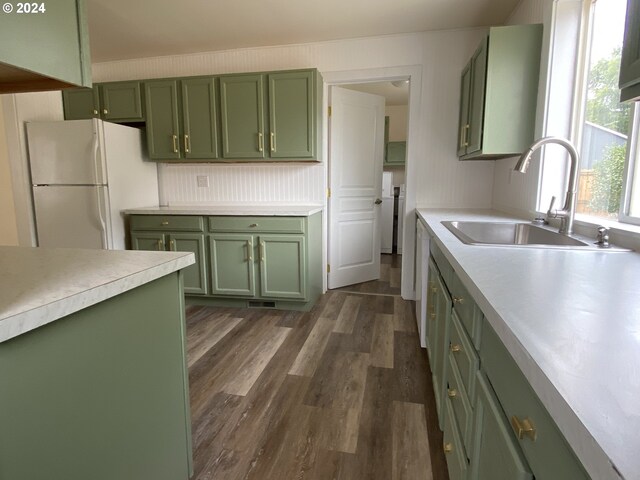 kitchen featuring sink, white refrigerator, dark hardwood / wood-style flooring, and green cabinets