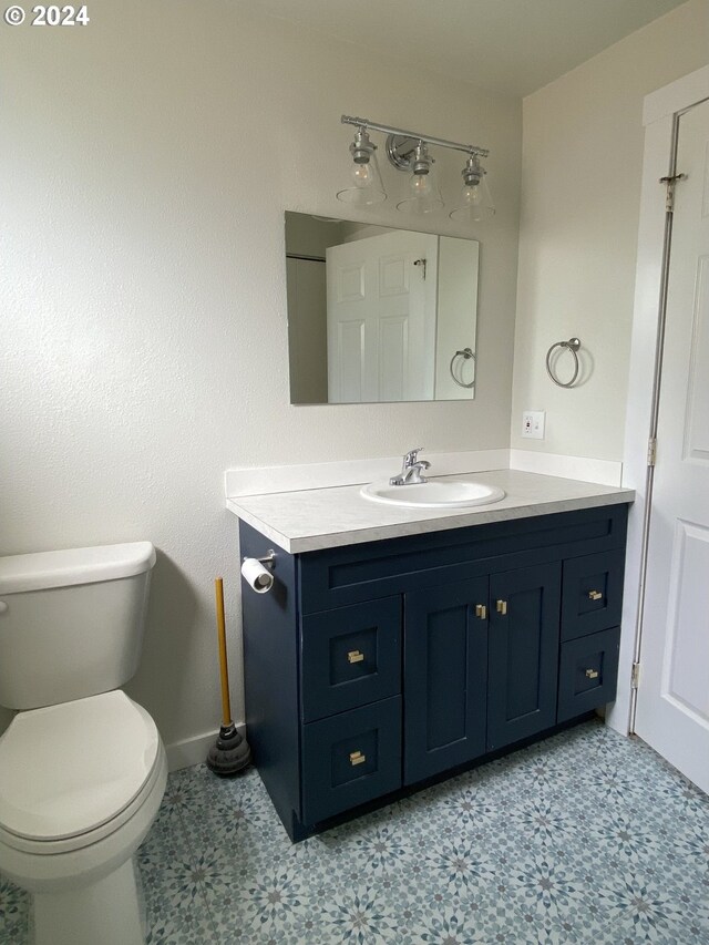 bathroom with toilet, tile patterned flooring, and vanity