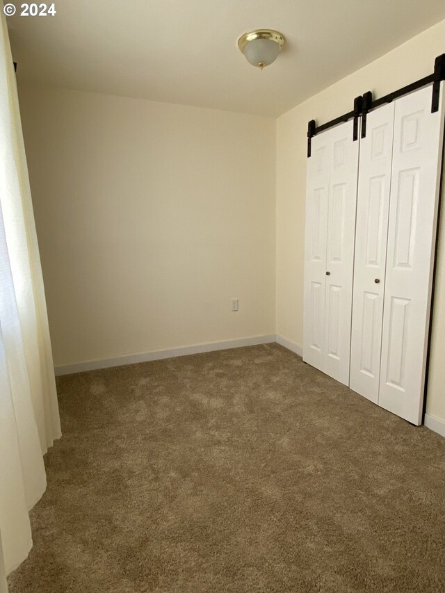 unfurnished bedroom featuring carpet floors and a barn door