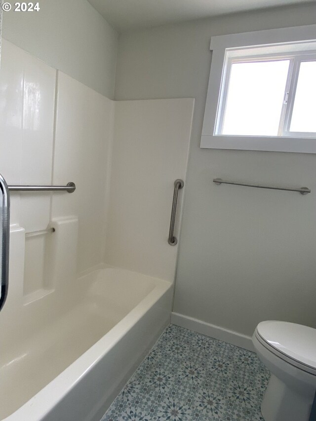 bathroom featuring washtub / shower combination, toilet, and tile patterned floors