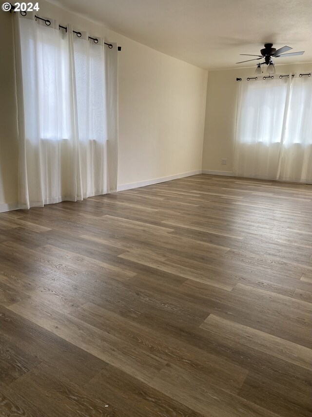 unfurnished room featuring ceiling fan, a healthy amount of sunlight, and dark hardwood / wood-style floors