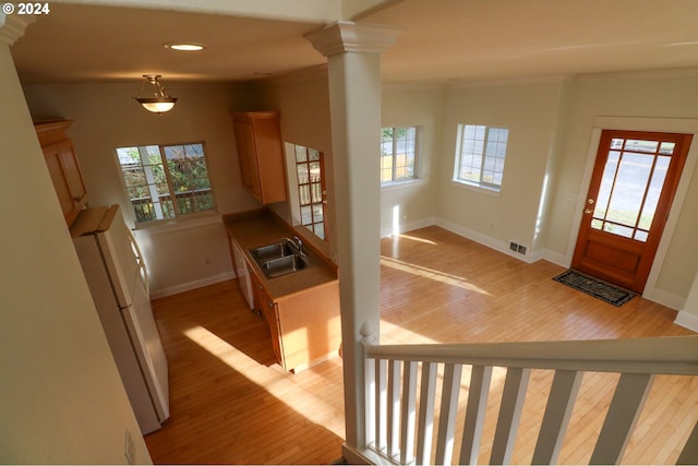 entrance foyer with decorative columns, light wood-type flooring, sink, and ornamental molding