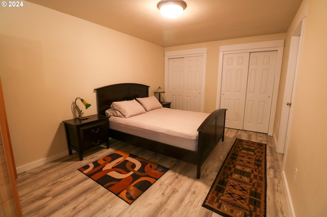 bedroom featuring light hardwood / wood-style floors and multiple closets