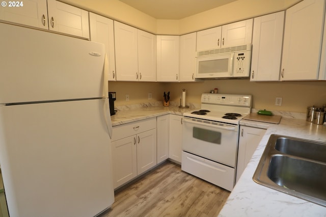 kitchen with sink, white cabinets, light hardwood / wood-style floors, and white appliances