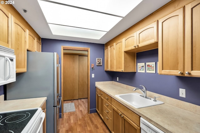 kitchen featuring sink, light hardwood / wood-style floors, white appliances, and light brown cabinets