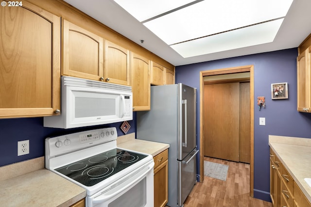 kitchen with light brown cabinetry, white appliances, and light hardwood / wood-style floors