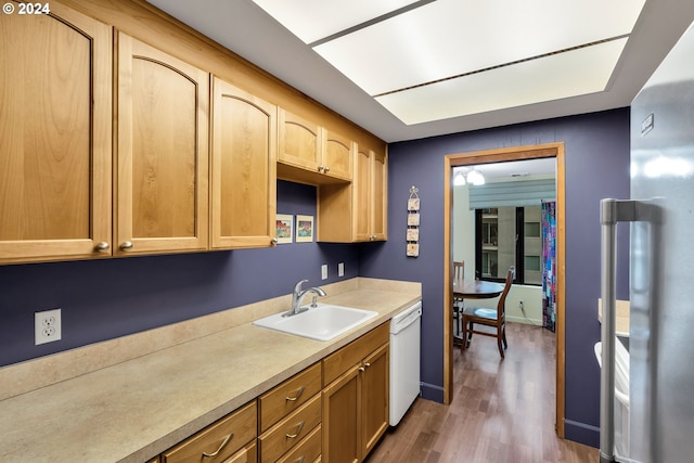 kitchen featuring light brown cabinets, dark wood-type flooring, white dishwasher, sink, and stainless steel refrigerator