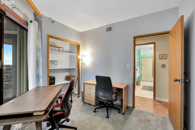 carpeted home office featuring a textured ceiling