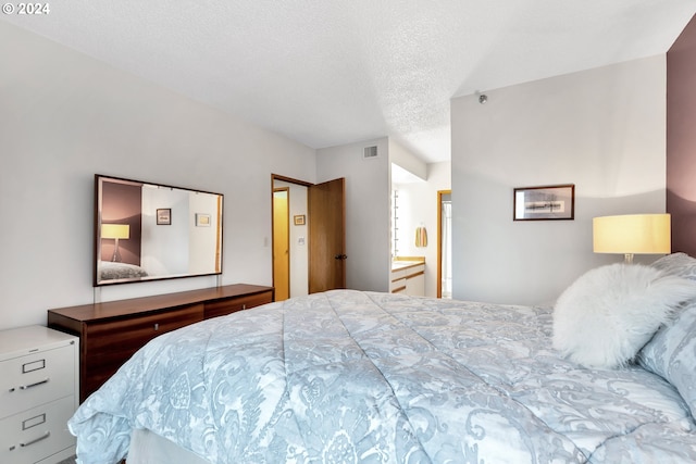 bedroom featuring ensuite bath and a textured ceiling