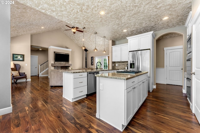 kitchen with kitchen peninsula, a kitchen island, stainless steel appliances, dark hardwood / wood-style flooring, and ceiling fan