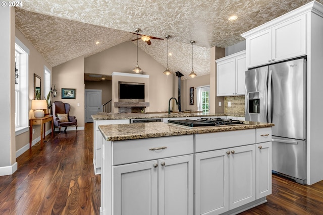 kitchen featuring kitchen peninsula, a kitchen island, a textured ceiling, dark wood-type flooring, and appliances with stainless steel finishes