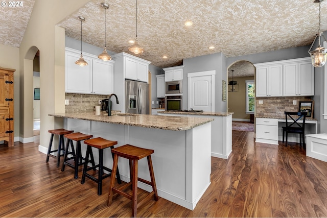 kitchen featuring pendant lighting, appliances with stainless steel finishes, dark wood-type flooring, and kitchen peninsula