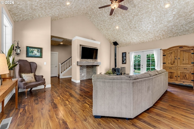 living room featuring ceiling fan, french doors, high vaulted ceiling, dark hardwood / wood-style floors, and a fireplace