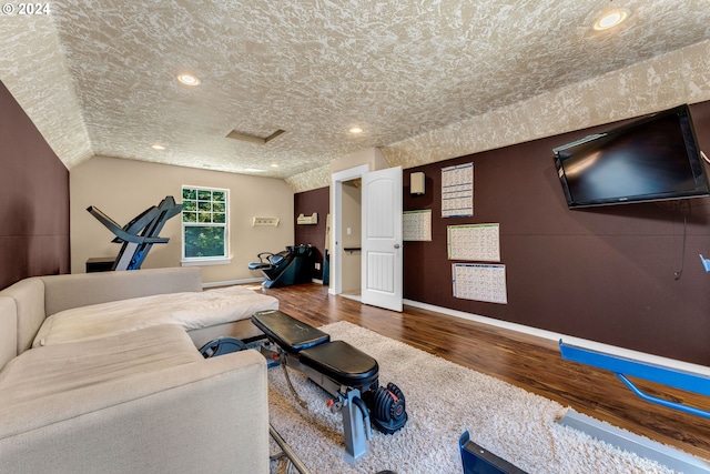 workout room with a textured ceiling, lofted ceiling, and hardwood / wood-style floors