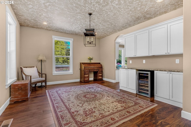 interior space with wine cooler, a textured ceiling, and dark wood-type flooring