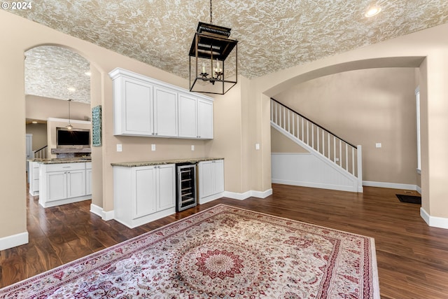 kitchen featuring white cabinets, beverage cooler, light stone countertops, and dark hardwood / wood-style flooring