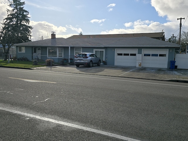 ranch-style house featuring driveway, a garage, and fence