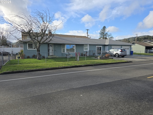 ranch-style home featuring a fenced front yard, an attached garage, and a front lawn