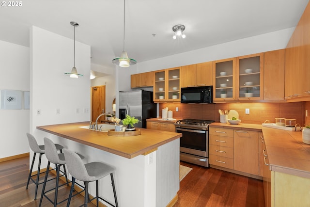 kitchen featuring sink, stainless steel appliances, tasteful backsplash, dark hardwood / wood-style floors, and pendant lighting