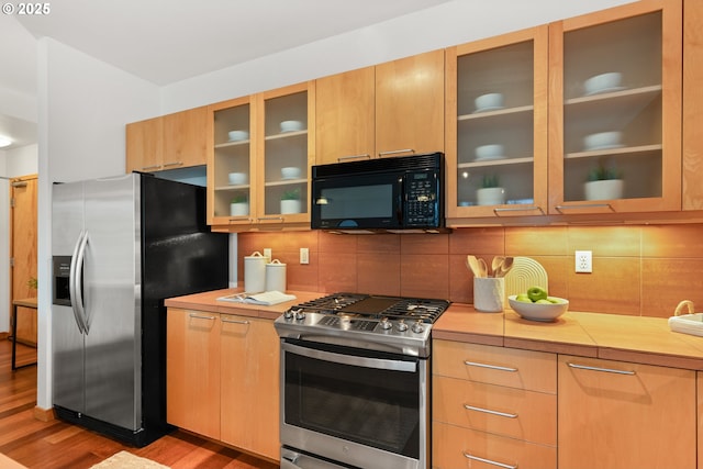 kitchen with light hardwood / wood-style floors, appliances with stainless steel finishes, and tasteful backsplash