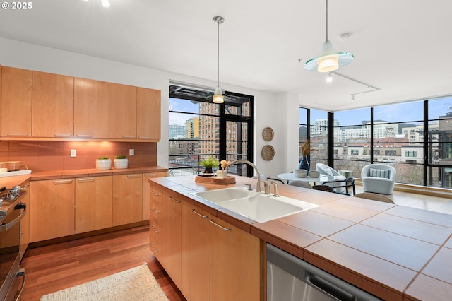 kitchen with sink, tile countertops, light hardwood / wood-style floors, decorative light fixtures, and decorative backsplash