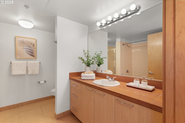 bathroom with vanity, toilet, tile patterned flooring, and tiled shower