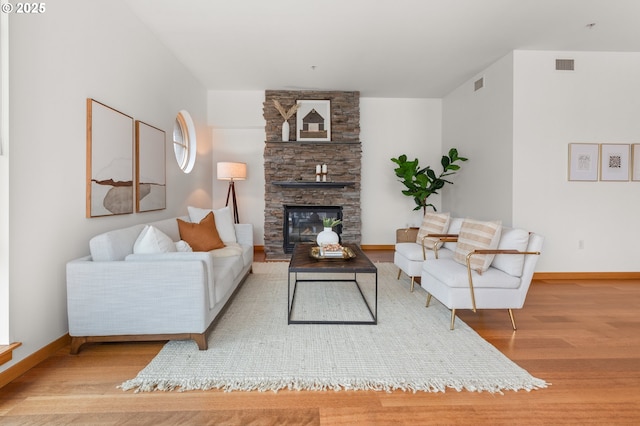 living room featuring a stone fireplace and light wood-type flooring