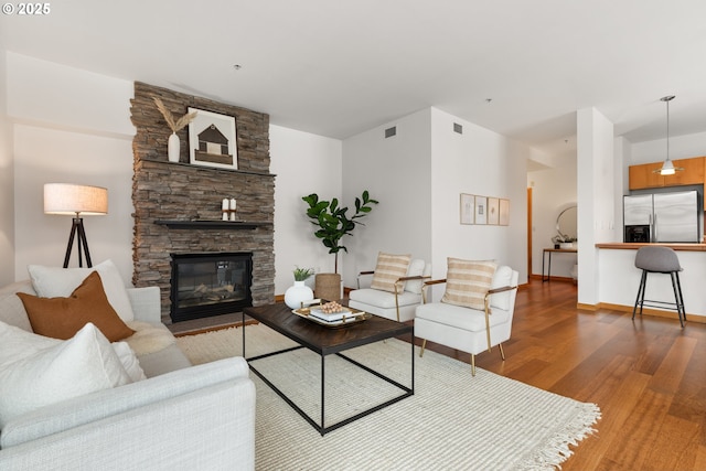 living room featuring a stone fireplace and hardwood / wood-style floors