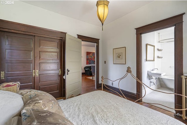 bedroom featuring dark wood-style floors, baseboards, and ensuite bath