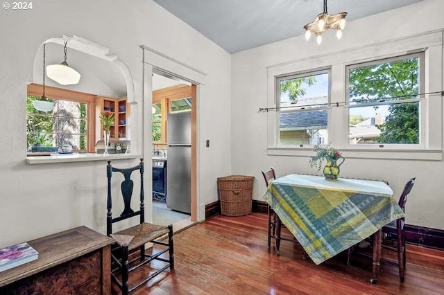 dining area with wood finished floors, plenty of natural light, and a chandelier