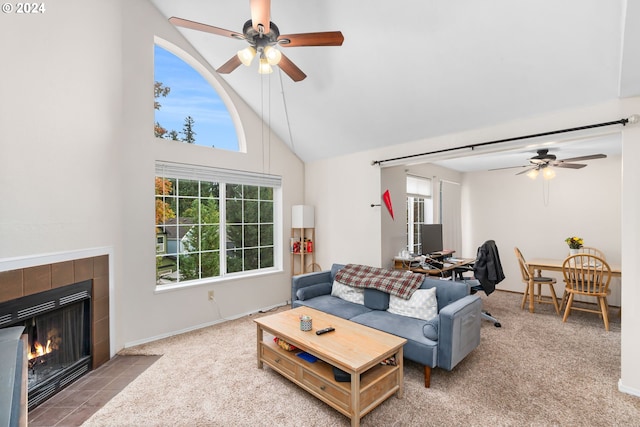 living room featuring ceiling fan, a tiled fireplace, high vaulted ceiling, and carpet floors