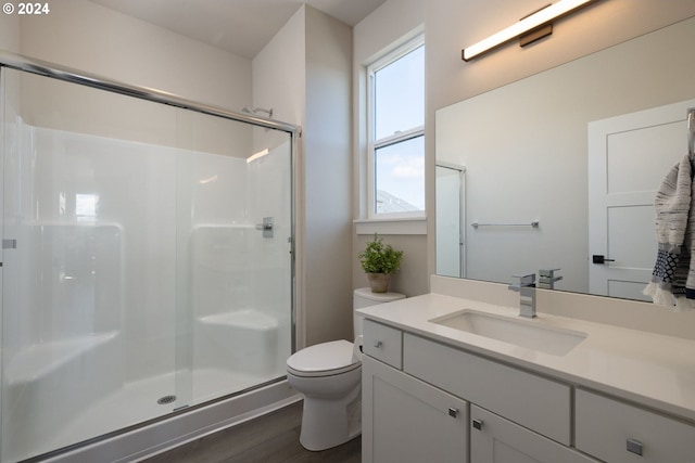 bathroom with toilet, vanity, hardwood / wood-style floors, and a shower with door