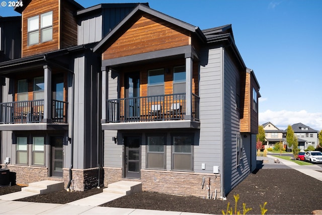 20536 Empire Ave, Bend, OR 97701 - view of front of property with a balcony, stone siding, entry steps, and board and batten siding