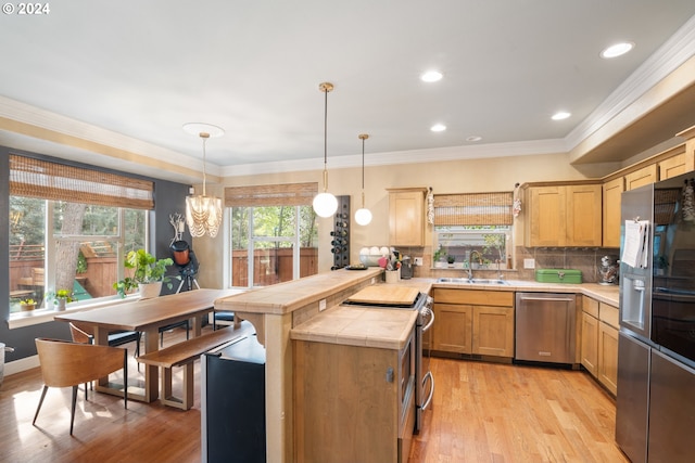 kitchen featuring tasteful backsplash, appliances with stainless steel finishes, light wood-type flooring, ornamental molding, and decorative light fixtures