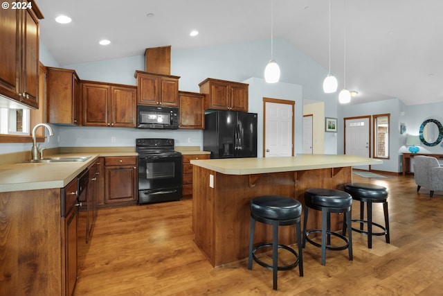 kitchen with sink, hardwood / wood-style flooring, black appliances, and a center island