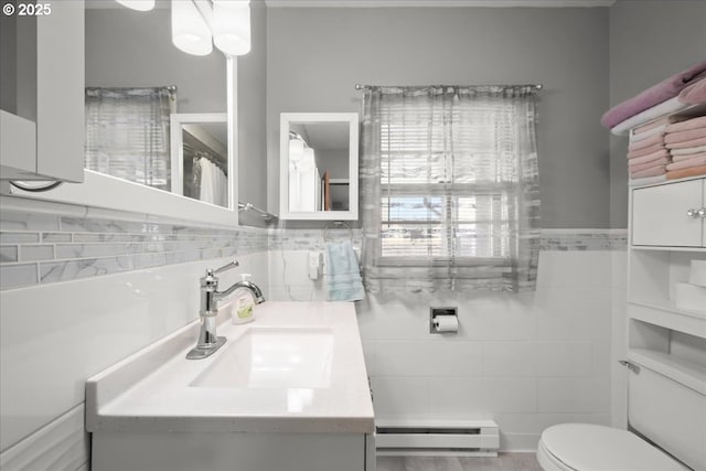 bathroom with vanity, tile walls, baseboard heating, and toilet