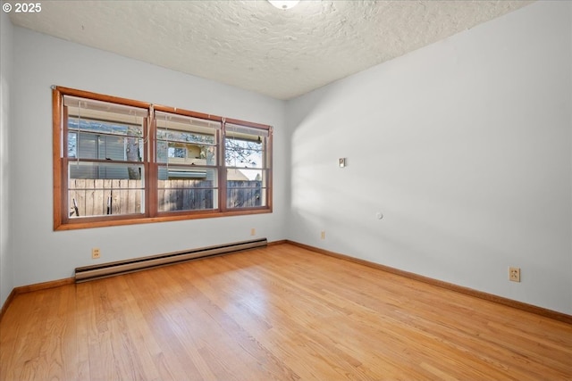 unfurnished room featuring baseboard heating, light hardwood / wood-style floors, and a textured ceiling