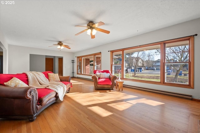 living room with ceiling fan, a baseboard heating unit, a textured ceiling, and light hardwood / wood-style floors